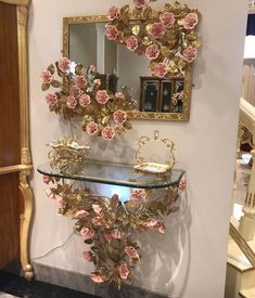 there is a glass shelf with pink flowers on it and a mirror above the shelf