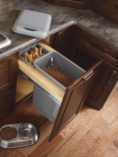 an open drawer in a kitchen next to a dog bowl and food dispenser