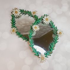 two mirrors with daisies on them are sitting on a table next to each other