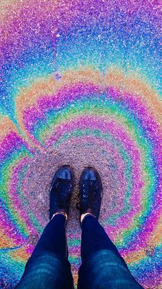 a person standing in front of a rainbow colored swirl on the ground with their feet up