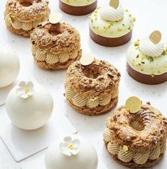 there are many different desserts on the table with white frosting and gold decorations