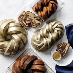 several different types of bundt cakes on cooling racks with coffee and saucers next to them