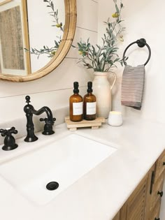 a white sink sitting under a mirror next to a faucet and soap dispenser