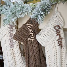 three sweaters hanging from a christmas tree with the word love spelled in wood letters