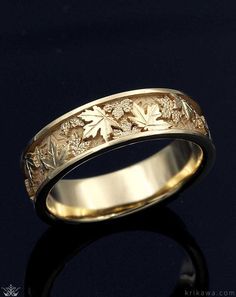 a wedding ring with leaves on it is shown in gold plated silver and has a black background