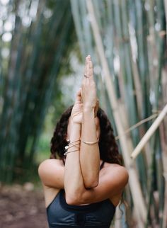 a woman standing in front of bamboo trees with her hands up to the side, doing yoga