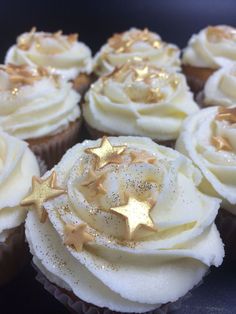 several cupcakes with white frosting and gold sprinkles on them