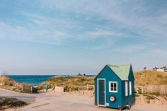 a small blue house sitting on top of a sandy beach