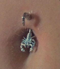 a close up of a person's belly with an ear piercing in the shape of a scorpion