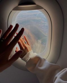 a person reaching out an airplane window to touch the hand of another person's arm