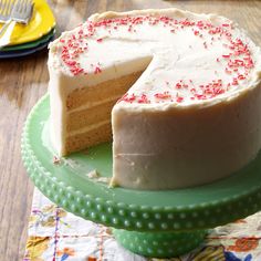 a cake with white frosting and red sprinkles on a green plate