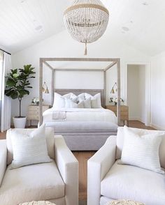 a bedroom with white furniture and a chandelier hanging from the ceiling