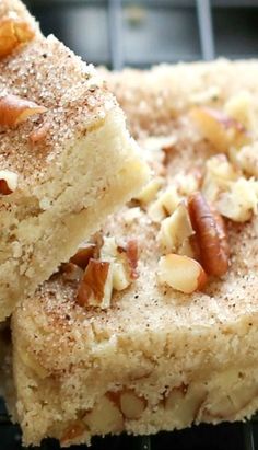 two pieces of cake sitting on top of a cooling rack covered in nuts and powdered sugar