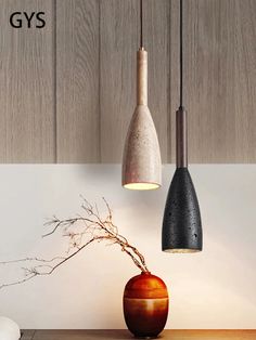 three lights hanging from the ceiling above a table with a vase and plant on it