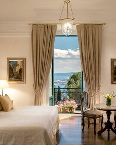 a bedroom with a large bed, two chairs and a table in front of a window