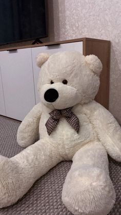 a large white teddy bear sitting on top of a bed