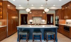 a large kitchen with an island in the middle and two stools at the center