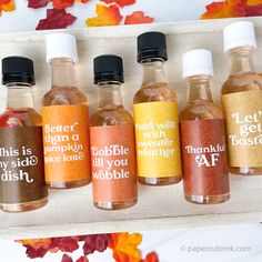 six bottles of different types of liquid in front of autumn leaves