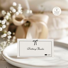 a white plate with a place card on it next to a bouquet of baby's breath flowers