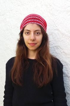 a woman with long hair wearing a red and white polka dot headband against a white wall