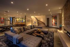 a living room filled with lots of furniture and a spiral staircase leading up to the second floor