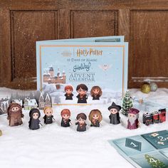 a harry potter christmas card and figurines in the snow next to a board game