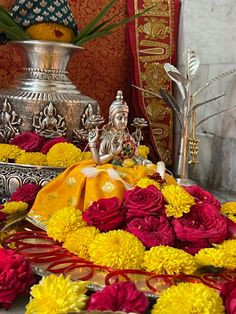 there are many flowers on the table with buddha statues in the backgrouf