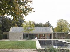 a house with a pool in front of it and lots of trees around the yard