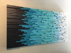 an abstract piece of wood with blue and black strips painted on the wall behind it