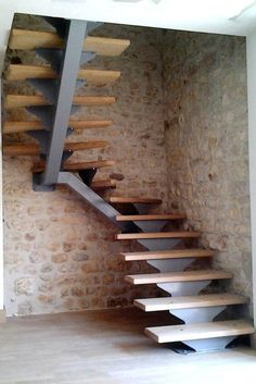 there is a spiral staircase in the room with stone walls and wood flooring on it