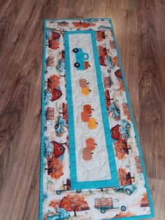 a quilted table runner on the floor with an orange and blue border around it