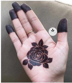 a woman's hand with a black rose tattoo on it