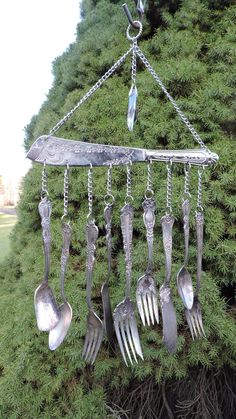 a bunch of spoons hanging from a chain with some forks attached to the chains