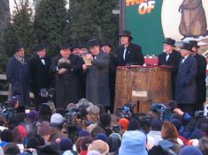 a group of men standing next to each other on top of a wooden barrel in front of a crowd