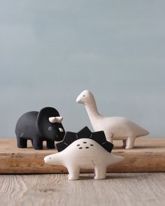 three black and white ceramic animals sitting on top of a wooden table next to each other