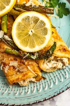 a blue plate topped with chicken, asparagus and lemon wedges on top of it