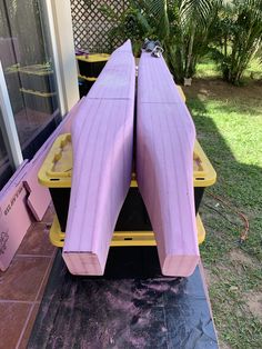 two large purple surfboards sitting on top of a black mat in front of a window