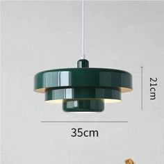 a green light hanging from the ceiling next to a white wall with measurements on it