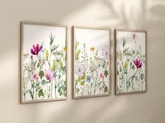 three floral paintings hang on the wall