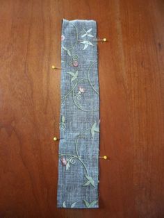 a piece of fabric with flowers on it sitting on a wooden table next to thread