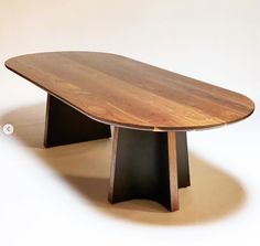 a wooden table sitting on top of a white floor next to a black metal object