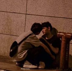 two young men sitting on the ground next to a fire hydrant with their arms around each other