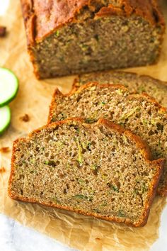 slices of zucchini bread sitting on top of a cutting board next to sliced cucumbers