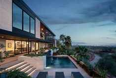 a modern house with an outdoor swimming pool and lounge chairs at the bottom of it