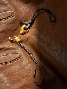 a brown leather bag with a gold colored handle and black cord on the inside of it