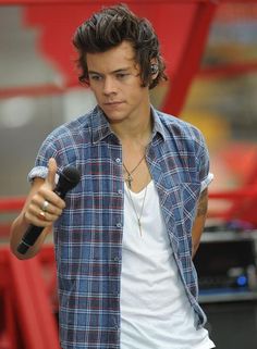 a young man holding a microphone in his right hand and wearing a plaid shirt on the left