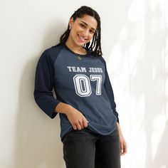 This Team Jesus Jersey Shirt is the perfect Christian shirt for any sports fan! It's a sporty stylish way to share your faith and heart for Jesus with anyone! Plus it's super soft and comfy. Whether your heading to your favorite sports game, running errands or a weekend get away, this cute Team Jesus shirt is a comfy casual Jesus shirt for any occasion. A stylish spin on the classic baseball raglan. The combed cotton blend makes it super soft, comfortable, and lightweight. You don’t even have to Navy Tops For Game Day During Sports Season, Casual Jersey T-shirt For Game Day, Team Spirit Game Day Tops With Moisture-wicking, Collegiate Navy Tops For Baseball Season, Collegiate Navy Top For Game Day, Navy Tops With Team Name For Football Season, Navy Varsity Top For College, Navy T-shirt For Game Day And Sports Season, Navy Team Name Football Tops