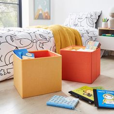 three books are sitting on the floor in front of a bed