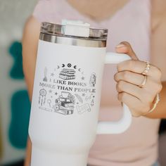 a woman holding a white coffee cup in her right hand and the words i like books more than people on it