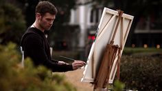 a man is painting on an easel outside